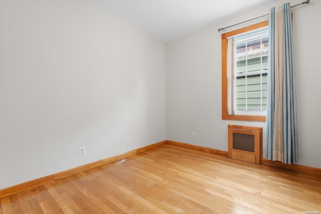 empty room with light hardwood / wood-style floors and heating unit