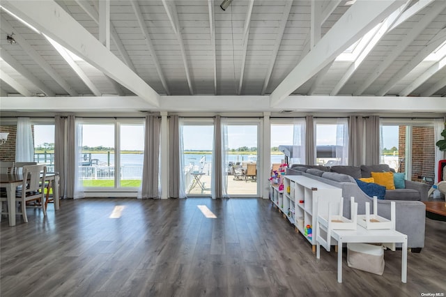 living room featuring beam ceiling, dark hardwood / wood-style flooring, a water view, and a wealth of natural light