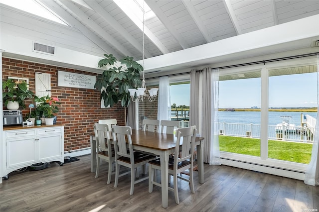 dining area featuring dark wood-type flooring, a water view, baseboard heating, beamed ceiling, and brick wall