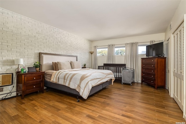 bedroom featuring hardwood / wood-style floors and brick wall