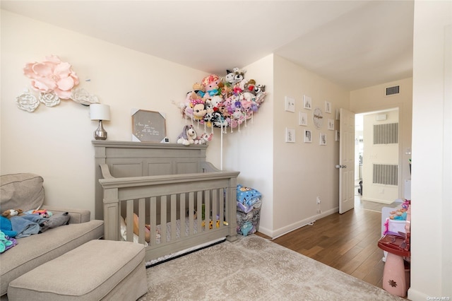 bedroom with hardwood / wood-style floors and a nursery area