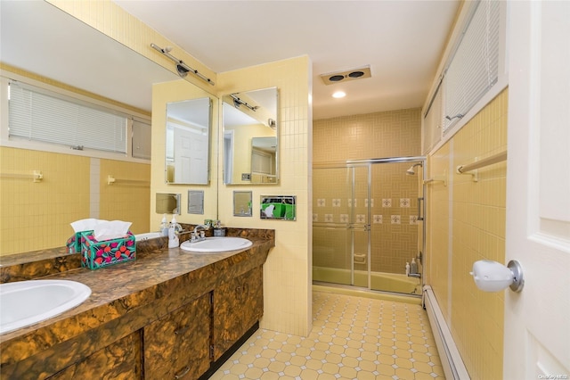 bathroom featuring vanity, a baseboard radiator, tile walls, and a shower with shower door