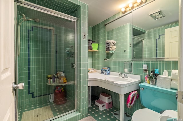 bathroom featuring toilet, a shower with door, tile walls, and sink