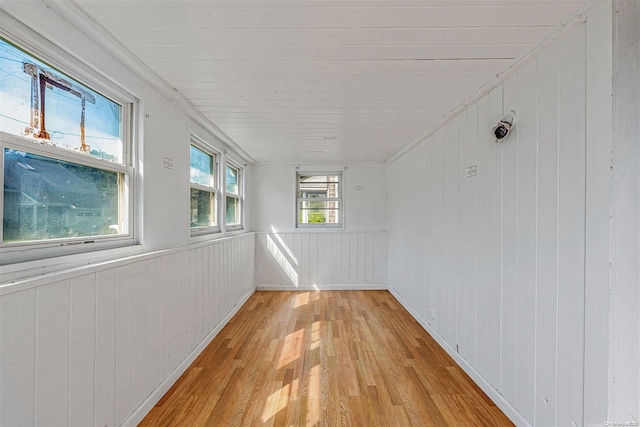 unfurnished room featuring light wood-type flooring and wooden walls