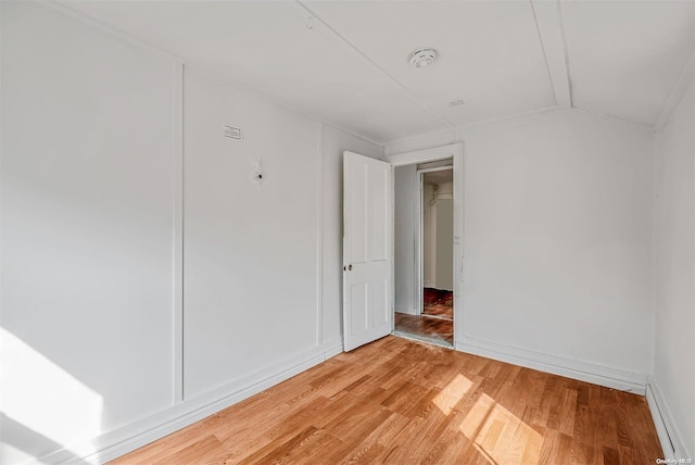 unfurnished room with light hardwood / wood-style floors, vaulted ceiling, and a baseboard radiator