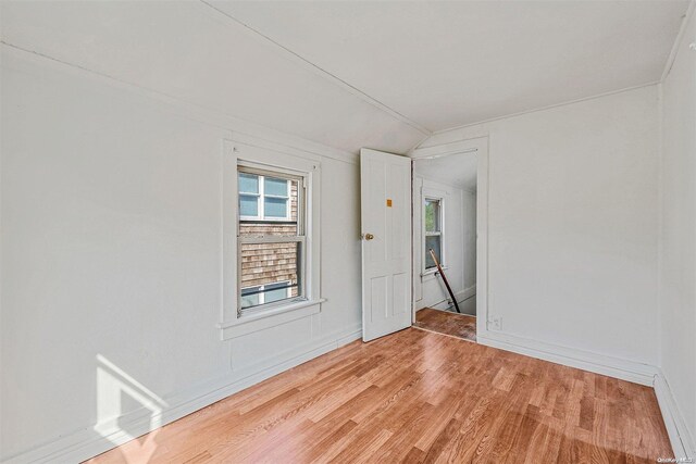 unfurnished room with lofted ceiling and light wood-type flooring