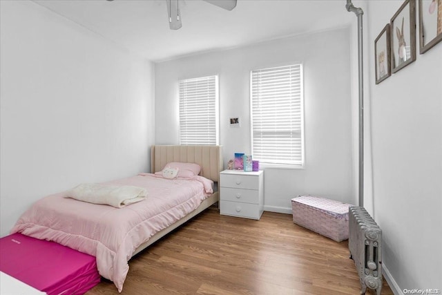 bedroom with wood-type flooring, radiator, and ceiling fan