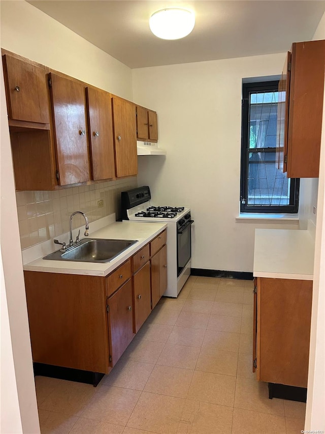 kitchen with backsplash, white gas stove, and sink