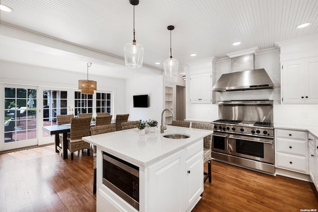 kitchen with a kitchen island with sink, range with two ovens, sink, wall chimney exhaust hood, and built in microwave