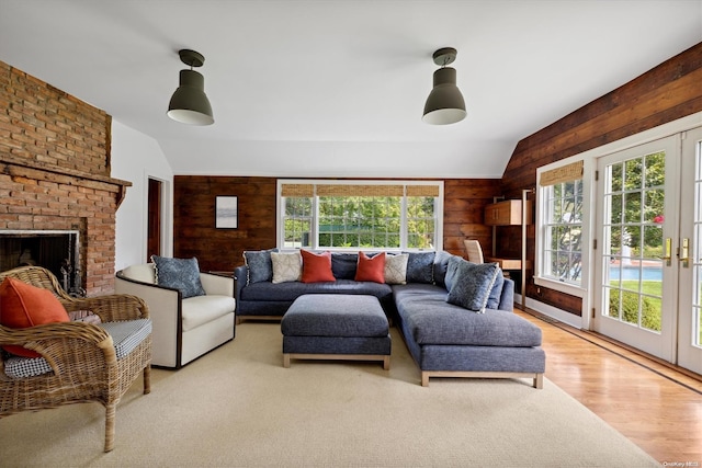 living room with a fireplace, light wood-type flooring, lofted ceiling, and wood walls