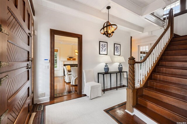 foyer with beam ceiling and an inviting chandelier