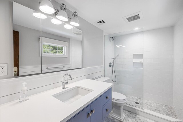 bathroom featuring vanity, toilet, and tiled shower