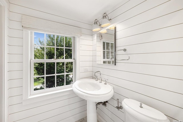 bathroom featuring wooden walls and toilet