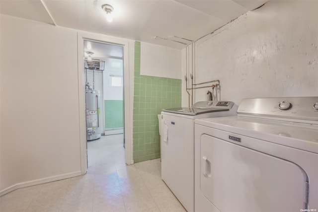 laundry room with washer and clothes dryer, tile walls, and water heater