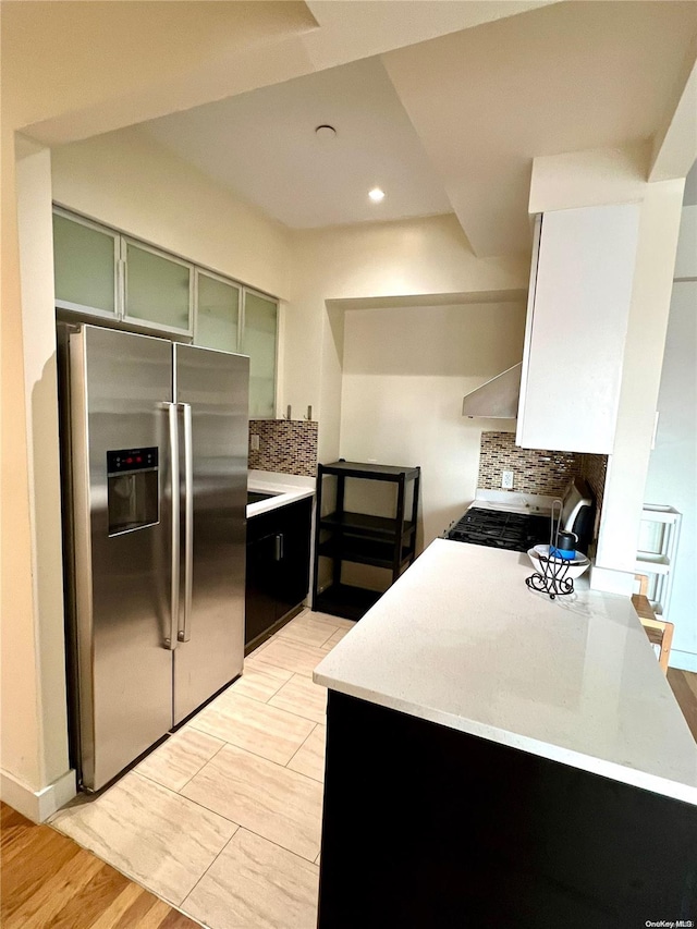 kitchen featuring stainless steel fridge with ice dispenser, green cabinetry, backsplash, stove, and light wood-type flooring