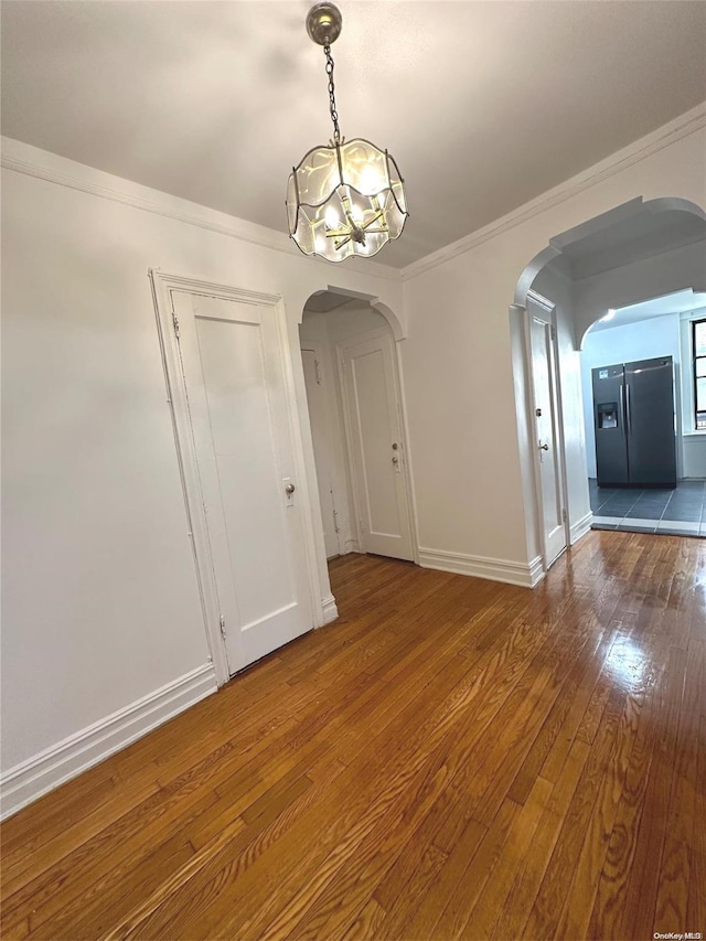 unfurnished dining area with ornamental molding, a chandelier, and hardwood / wood-style flooring