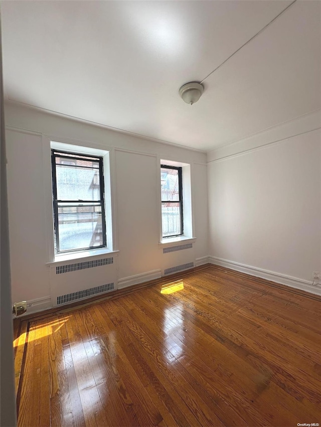 empty room featuring wood-type flooring and radiator