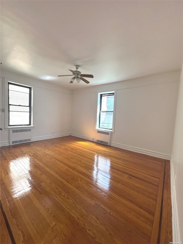 unfurnished room with radiator, ceiling fan, and hardwood / wood-style flooring