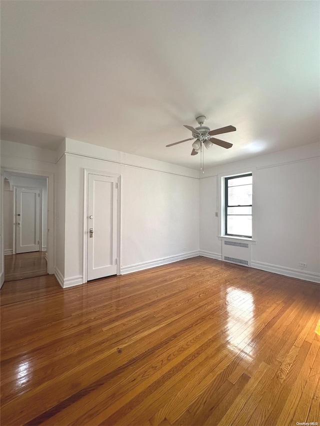 unfurnished room featuring ceiling fan, wood-type flooring, and radiator heating unit