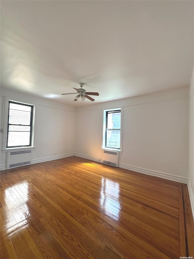 spare room with hardwood / wood-style flooring, ceiling fan, and radiator