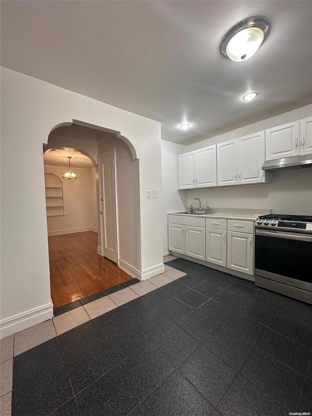 kitchen with sink, stainless steel range oven, white cabinetry, and dark wood-type flooring