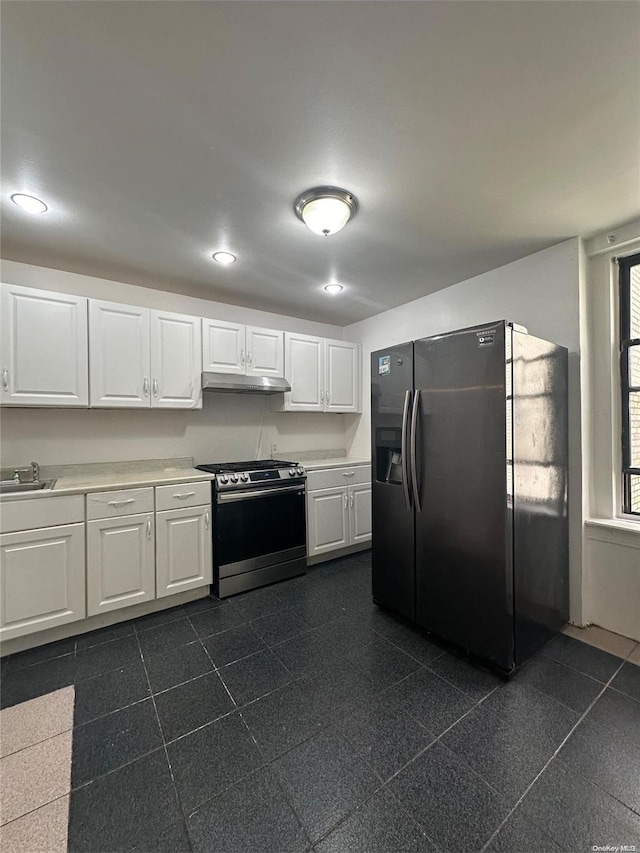 kitchen featuring stainless steel range oven, white cabinetry, sink, and black fridge