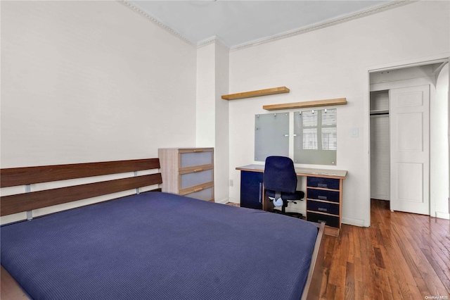 bedroom with dark hardwood / wood-style flooring, crown molding, and a closet