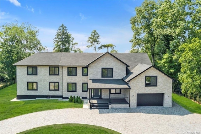 view of front of home featuring a front lawn, covered porch, and a garage