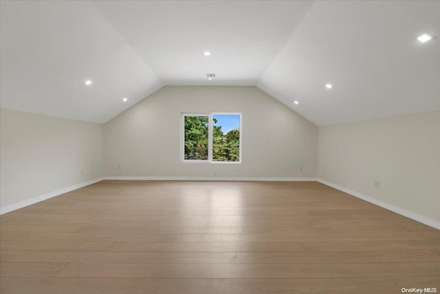 additional living space with vaulted ceiling and light hardwood / wood-style flooring