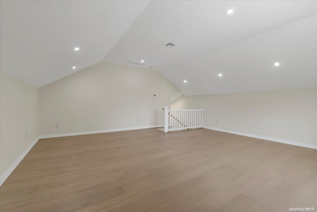 additional living space with light wood-type flooring and vaulted ceiling