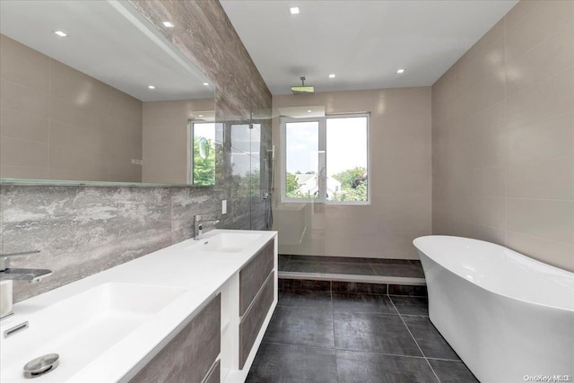 bathroom with tile patterned flooring, vanity, tile walls, and a bathing tub