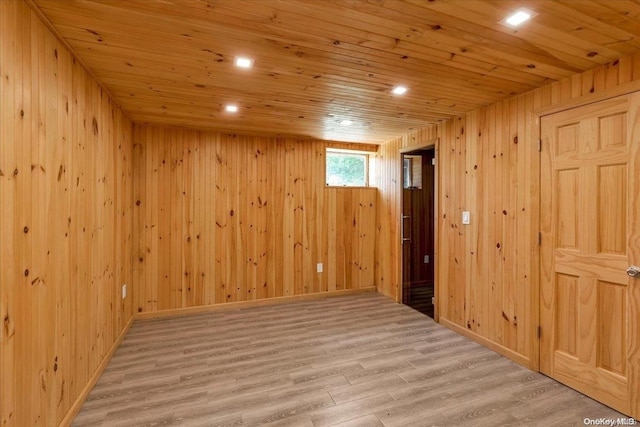 basement featuring light wood-type flooring, wooden ceiling, and wood walls