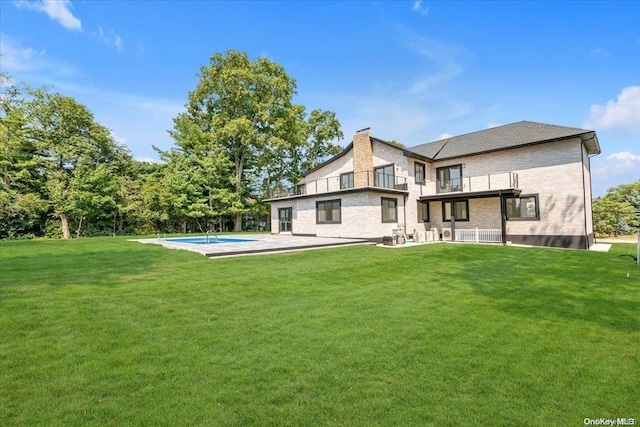 back of property with a balcony, a yard, and a patio