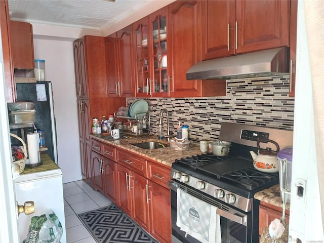 kitchen featuring stainless steel gas stove, sink, tasteful backsplash, light stone counters, and light tile patterned flooring