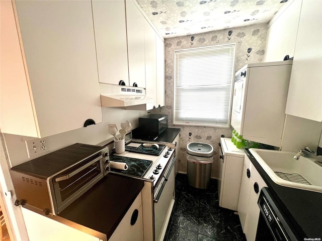 kitchen with white stove, washer / dryer, white cabinetry, and sink