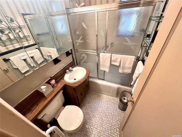 full bathroom featuring tasteful backsplash, vanity, bath / shower combo with glass door, and toilet