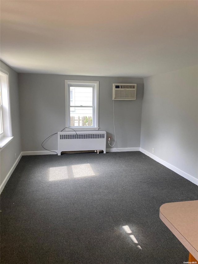 carpeted empty room with a wall mounted AC and radiator