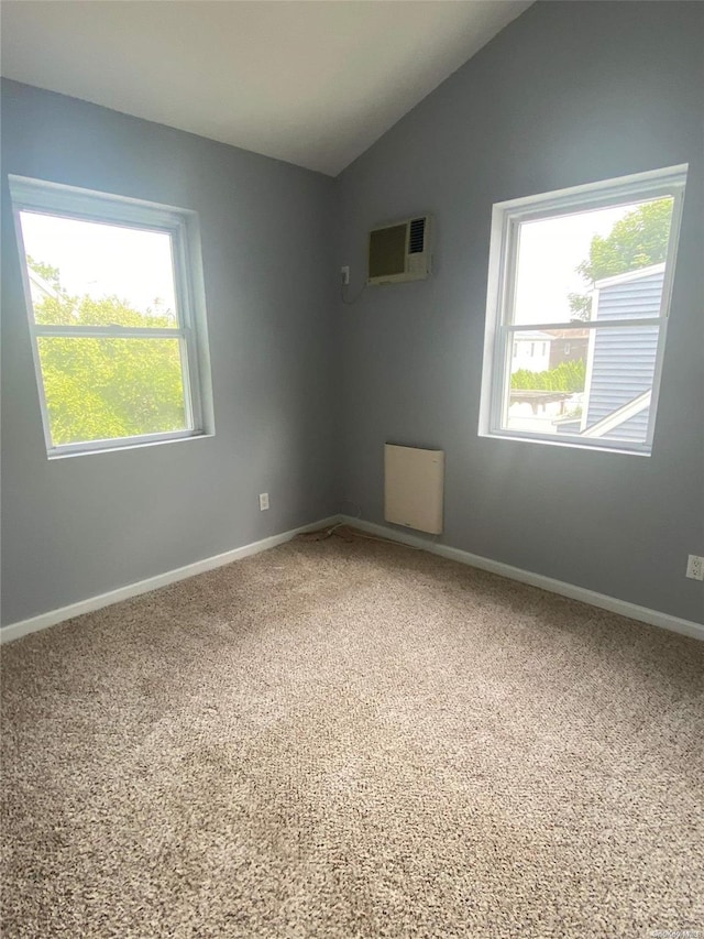 carpeted empty room with an AC wall unit and vaulted ceiling