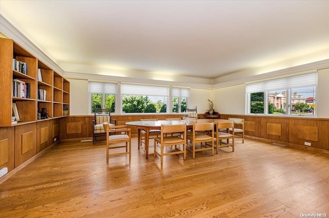 dining area with a wealth of natural light, light hardwood / wood-style flooring, and wood walls