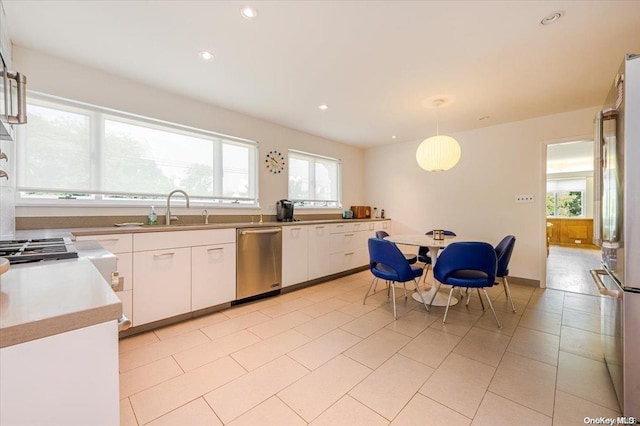 kitchen featuring white cabinetry, sink, stainless steel appliances, decorative light fixtures, and light tile patterned flooring