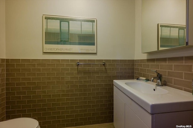 bathroom with vanity, tile walls, and toilet