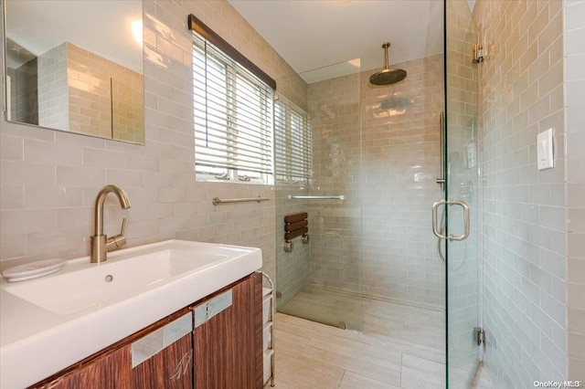 bathroom featuring tile patterned floors, vanity, a shower with door, and tile walls