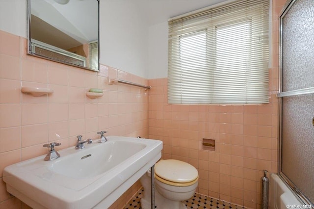 full bathroom with bath / shower combo with glass door, toilet, tile walls, and sink