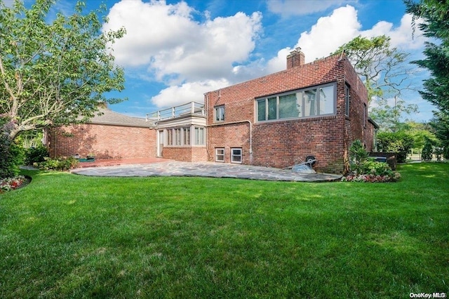 back of house featuring a lawn, a balcony, and a patio