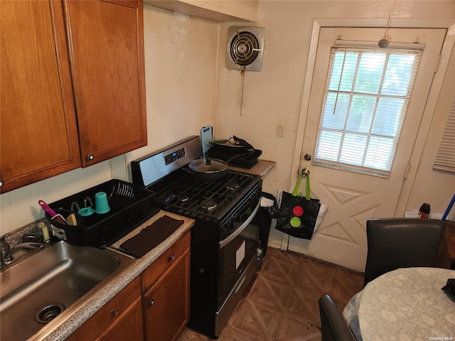 kitchen with gas stove, dark parquet flooring, and sink