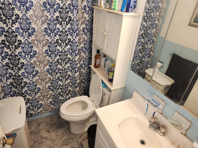 bathroom featuring tile patterned flooring, vanity, toilet, and tile walls