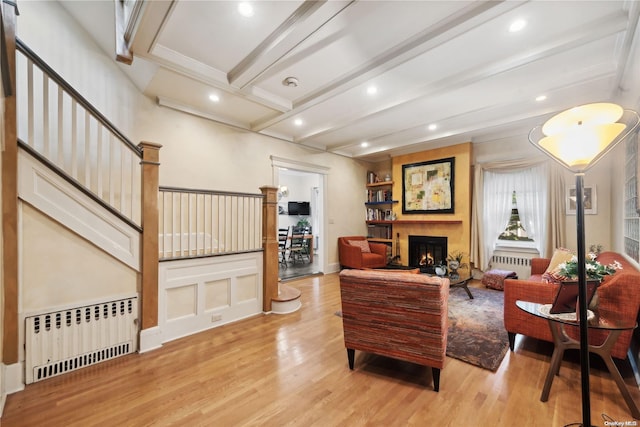 living room featuring light hardwood / wood-style floors, beam ceiling, and radiator