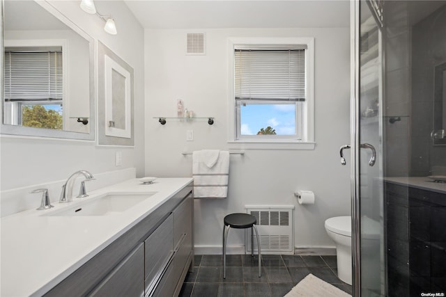 bathroom featuring vanity, a shower with door, radiator, tile patterned floors, and toilet