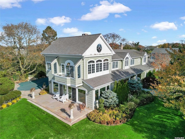 back of house featuring a patio, a balcony, and a lawn