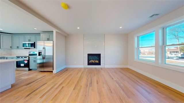 unfurnished living room featuring a fireplace, plenty of natural light, and light hardwood / wood-style flooring